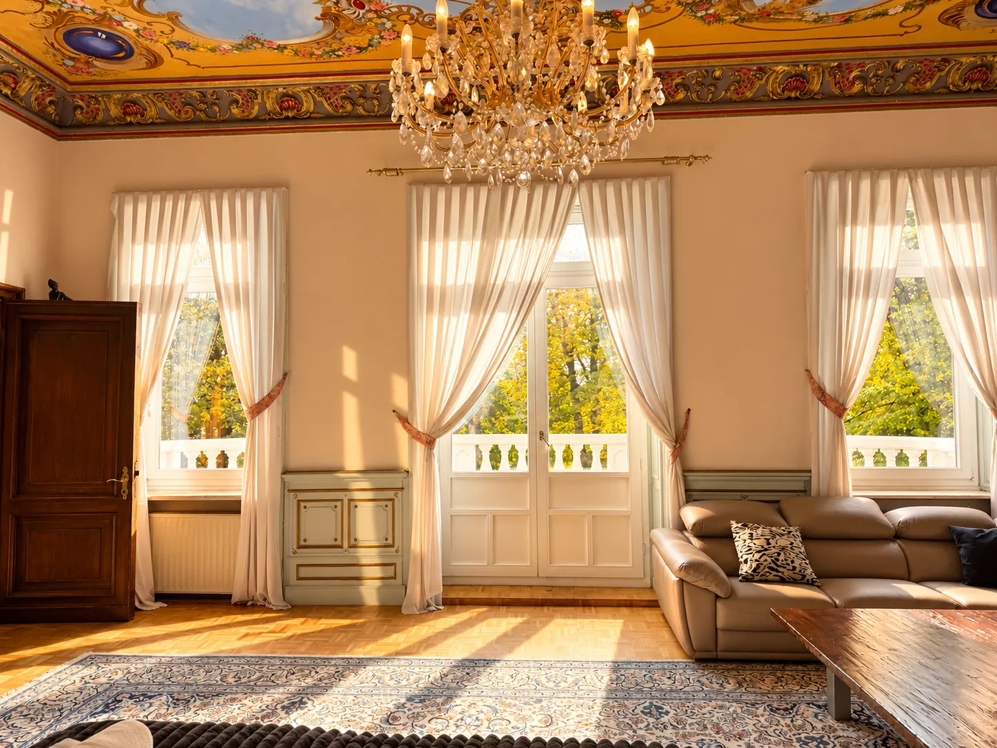 Salon mit Ledersofa und hohen Fenstertüren